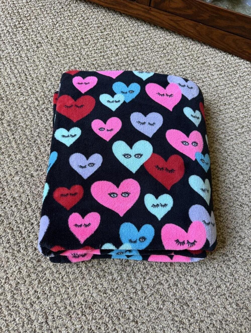 Black blanket with pink, red, and light blue hearts with eyelashes